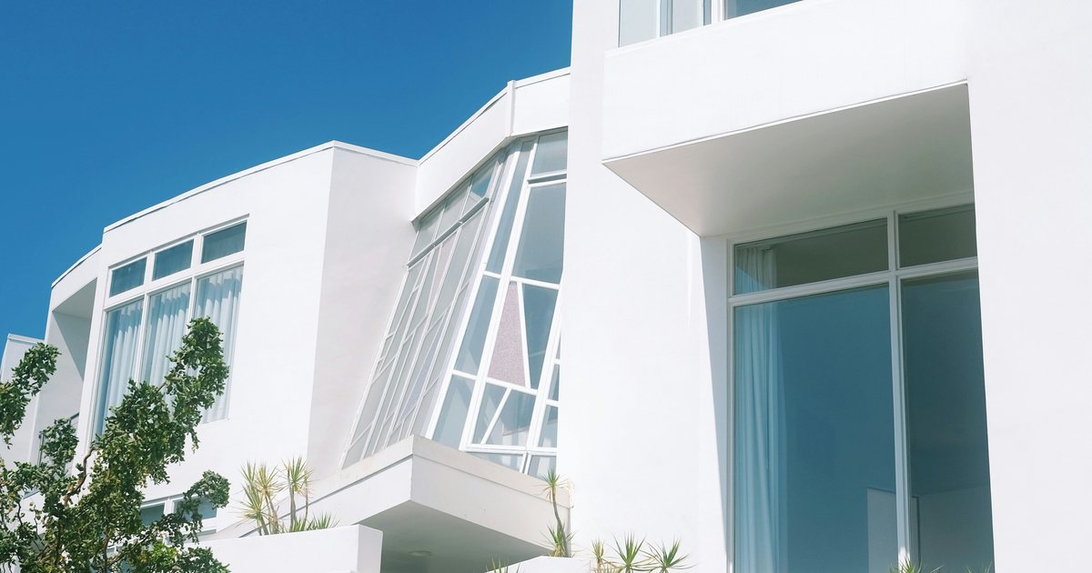 Weißes Ferienhaus mit großen Fensterfronten vor blauem Himmel