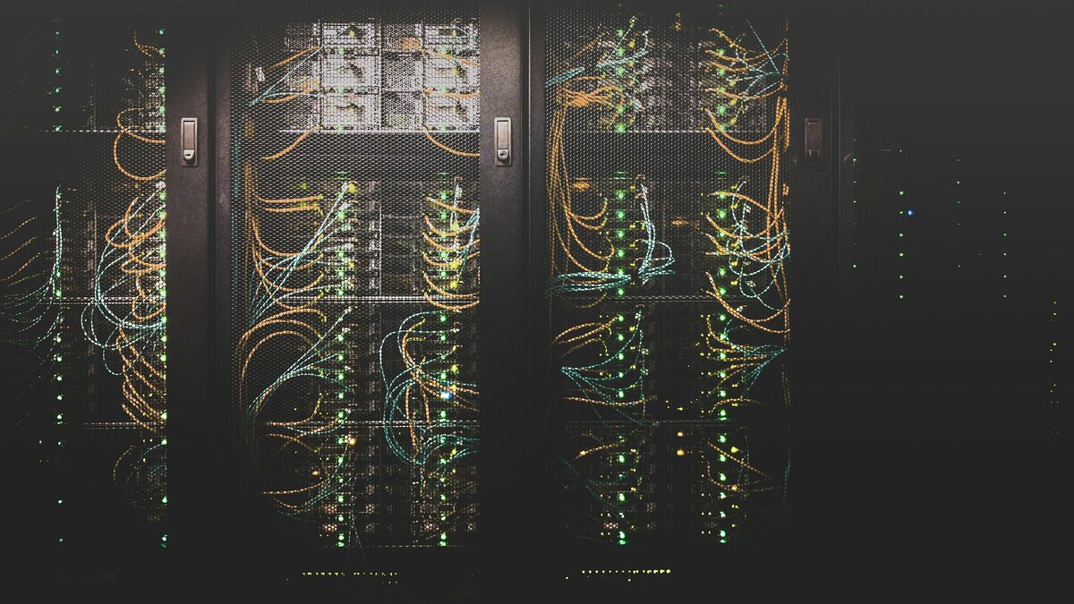 Serverschränke in einem dunklen Rechenzentrum mit gelben Netzwerkkabeln und grünen Kontrollleuchten