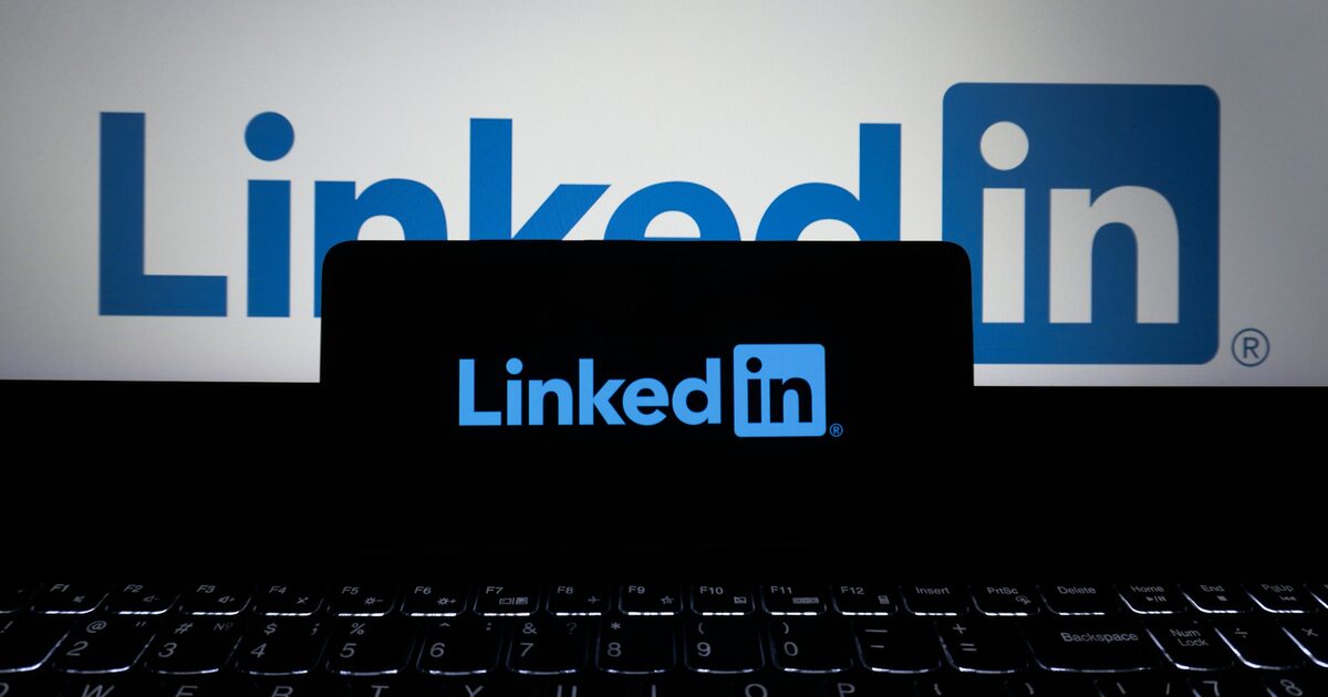 LinkedIn-Logo auf einem Smartphone vor einem Laptop, auf dessen Bildschirm ebenfalls das LinkedIn-Logo zu sehen ist