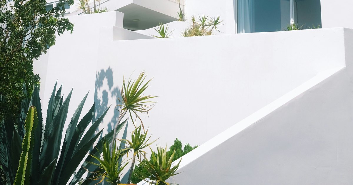 Weiße Terrassenmauern eines Ferienhauses mit Agaven und Kakteen im Vordergrund